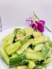 A plate of cucumber salad with a purple flower on top.