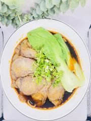 A white plate topped with meat and lettuce on a table.