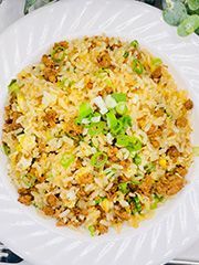 A white plate topped with rice , meat and green onions.