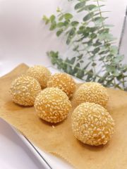 A plate of sesame seed balls on a table with a plant in the background.