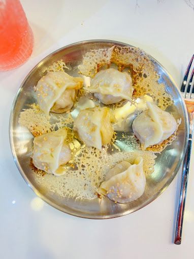A plate of dumplings with a fork on a table.