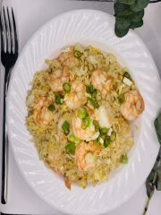 A white plate topped with shrimp and rice next to a fork.