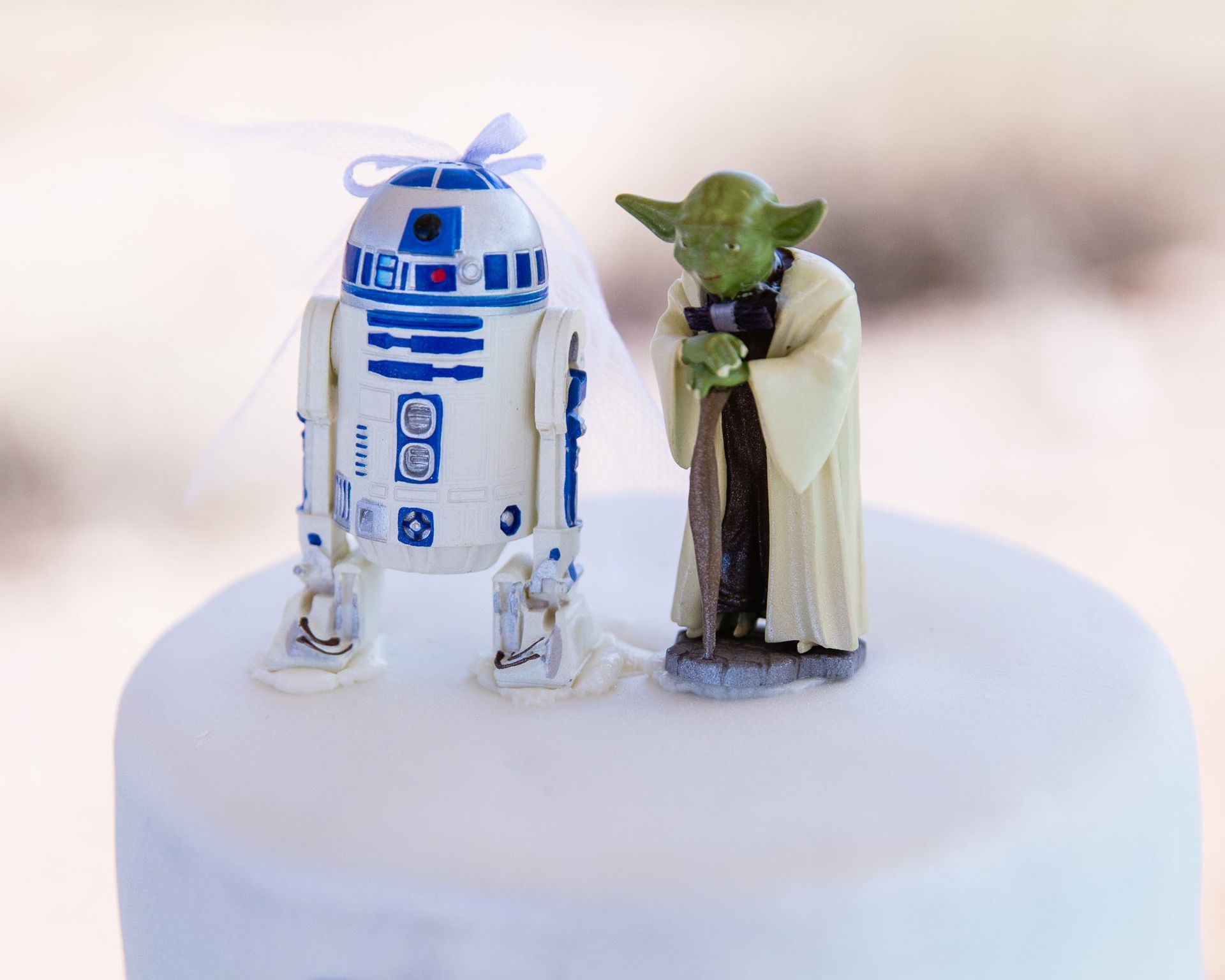 R2-D2 and Yoda figurines standing together on a white cake