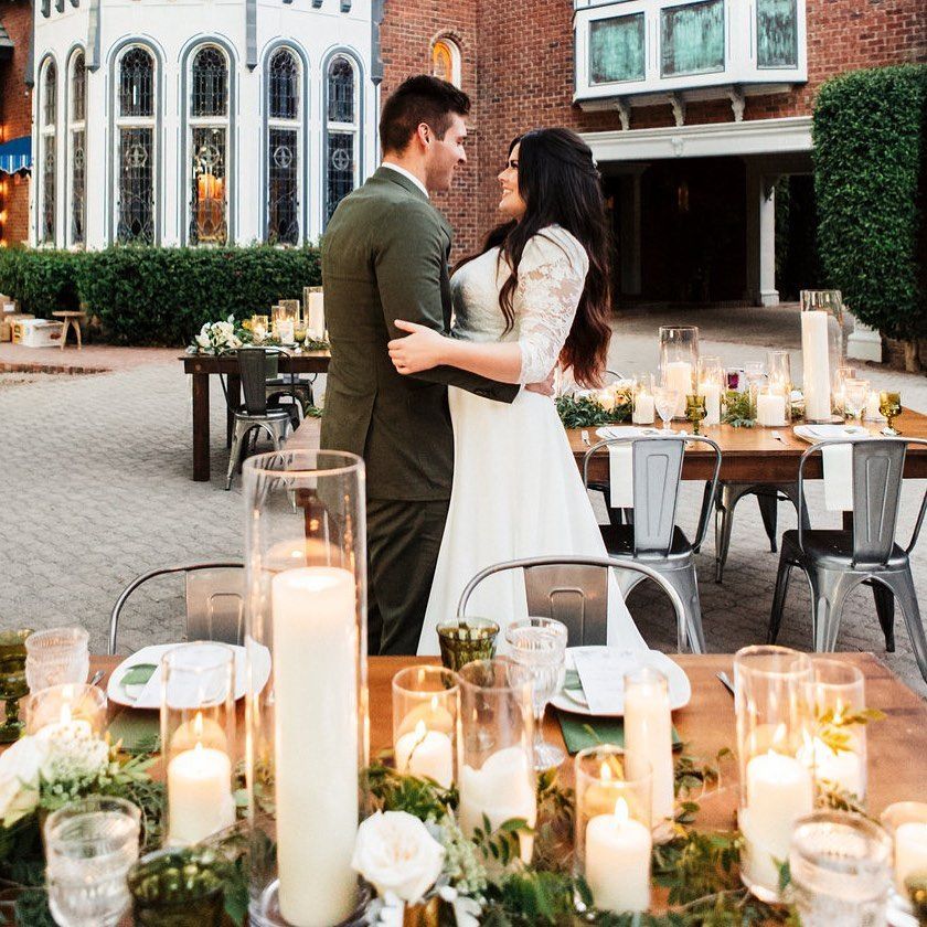 Couple embracing at a candlelit outdoor dinner by a brick building