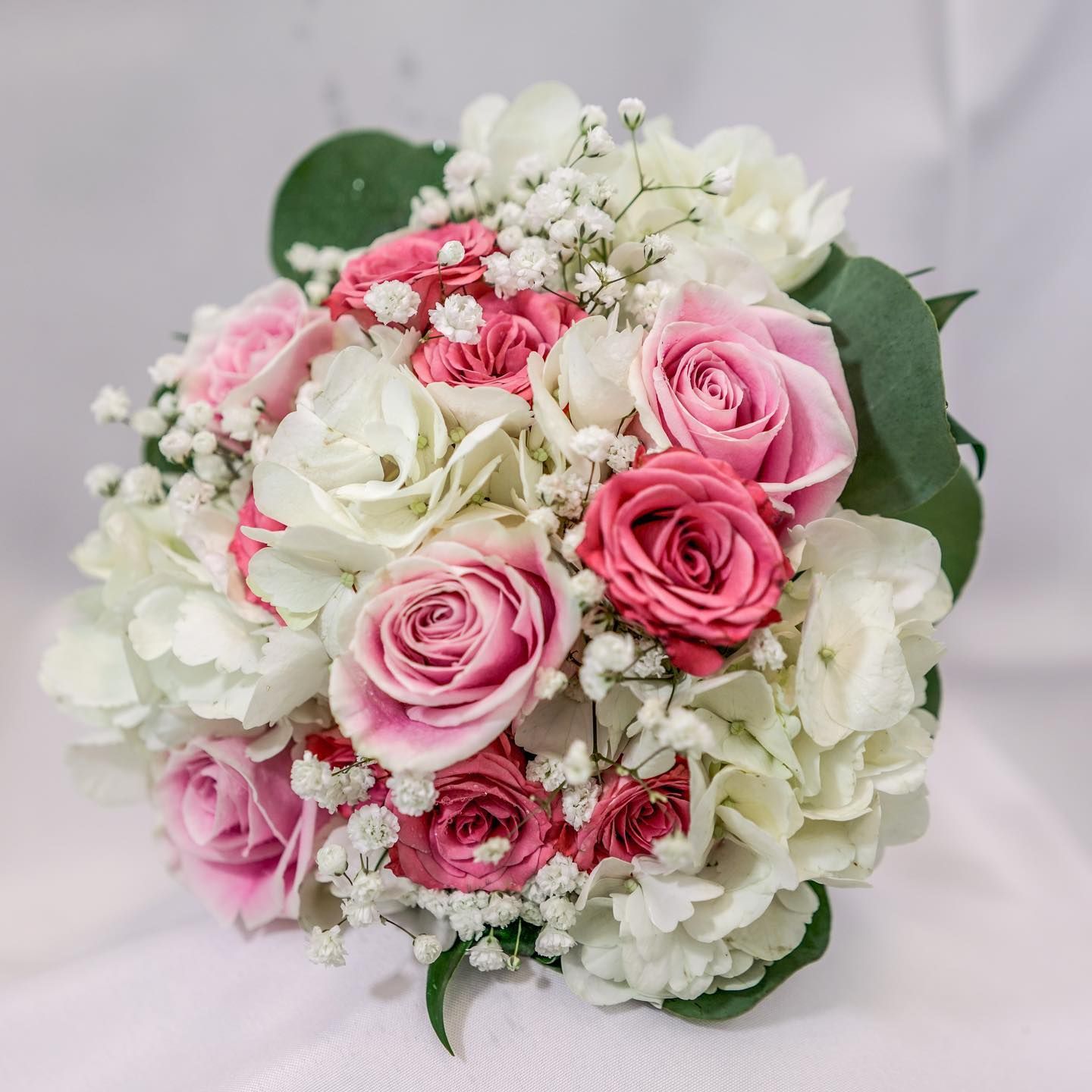 Pink and white rose bouquet with greenery on a light background