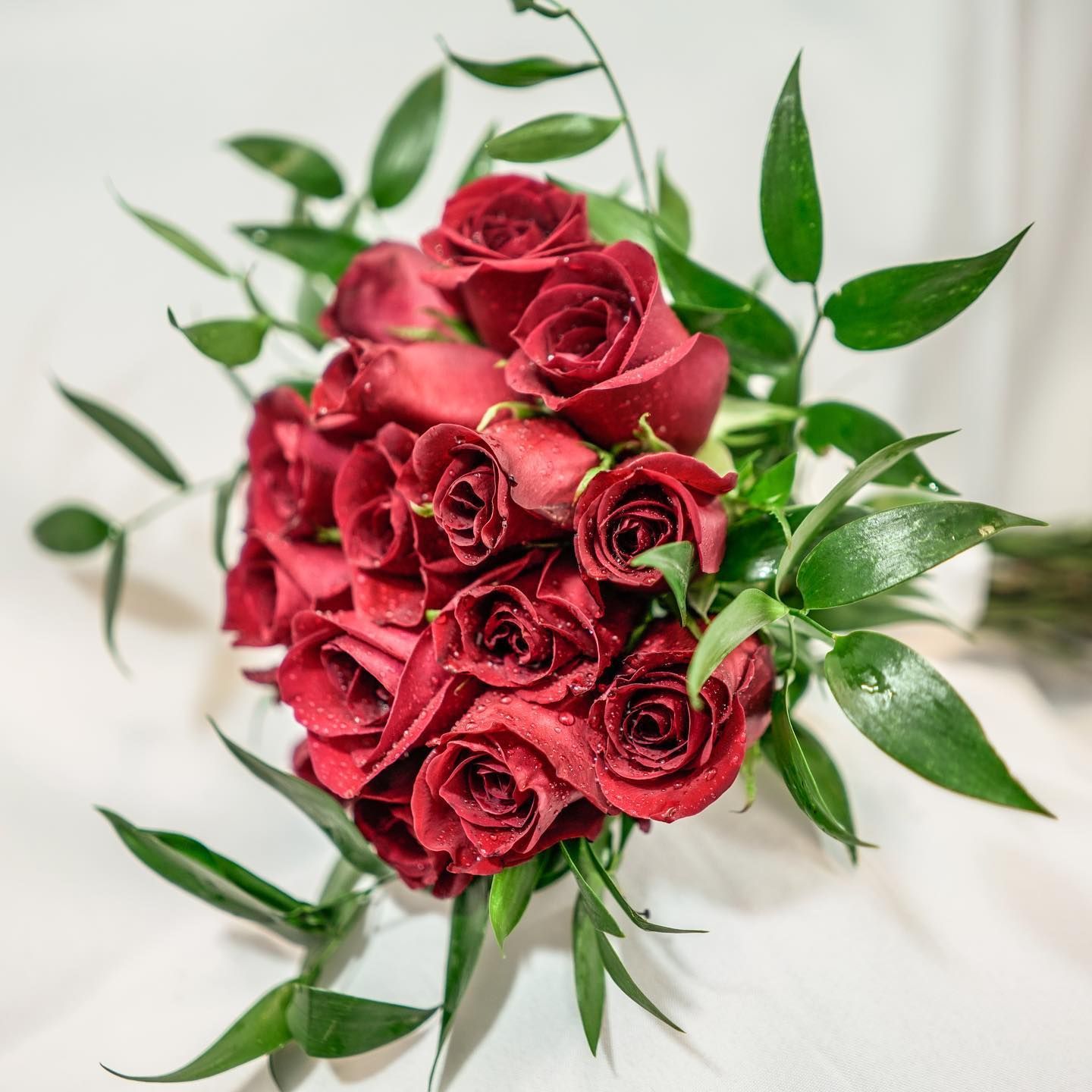 Bouquet of deep red roses with green leaves on a white background