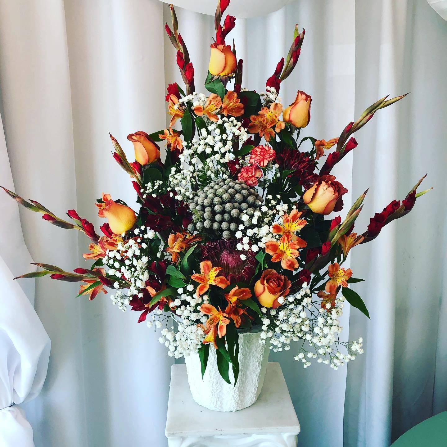 Autumn floral arrangement with orange roses and berries in a white vase on a table