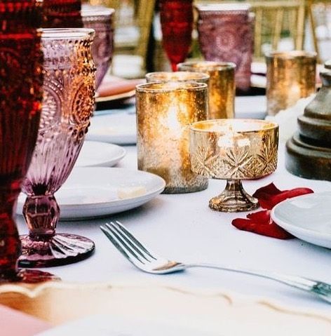 Elegant table setting with gold and red glass candleholders and white plates