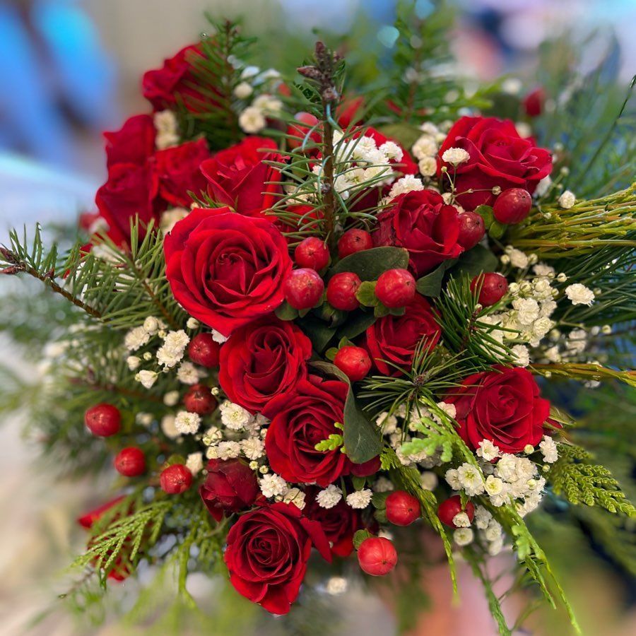 Red rose bouquet with white baby's breath, berries, and greenery on a blurred background