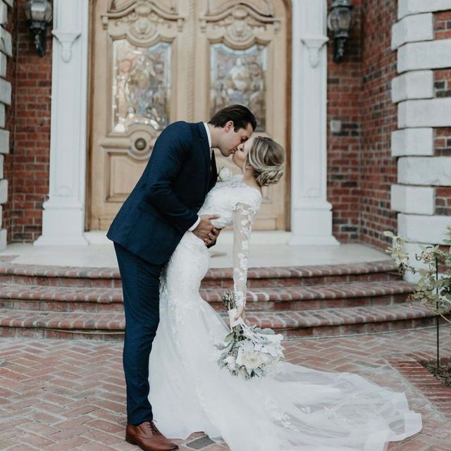 Bride and groom kissing outside a brick building with ornate wooden doors