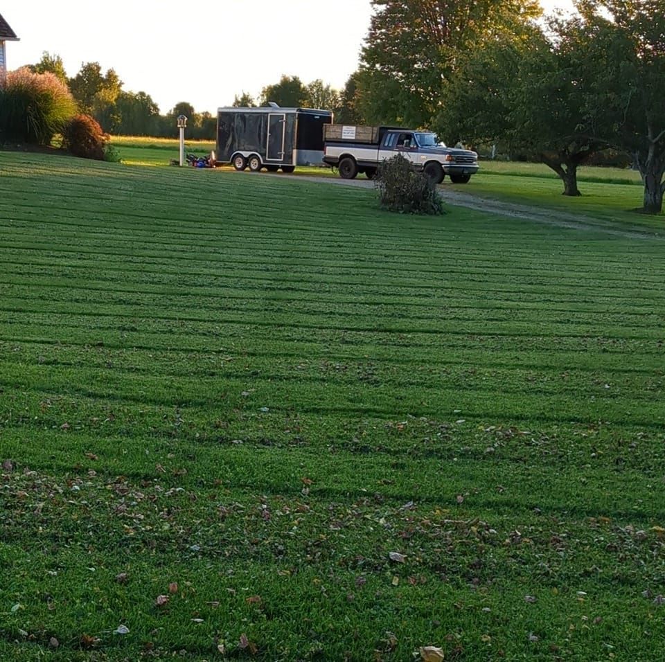 Green lawn with a truck and trailer parked.