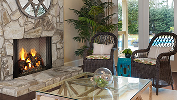 A living room with a fireplace , chairs , a coffee table and a mirror.