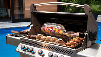 A grill with food on it is sitting next to a pool.