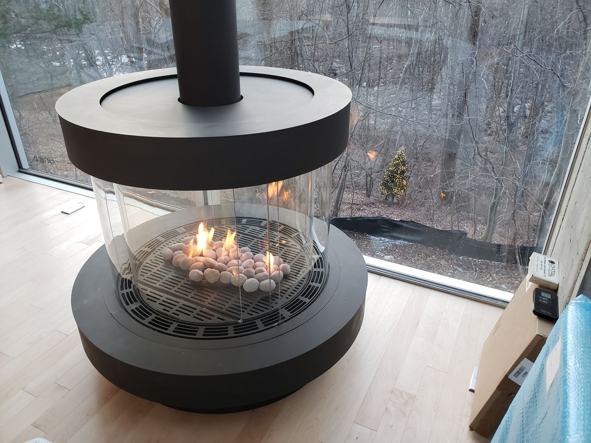 A fireplace is sitting on a wooden floor in front of a window.