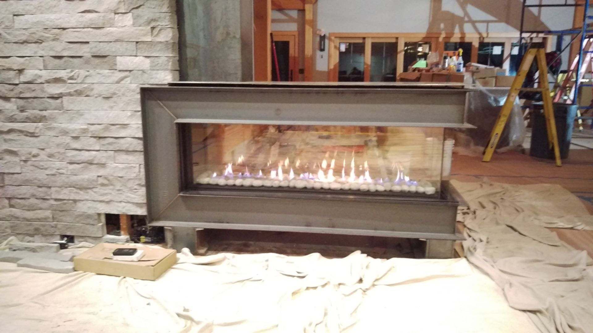 A fireplace is being built in a room with a ladder in the background.