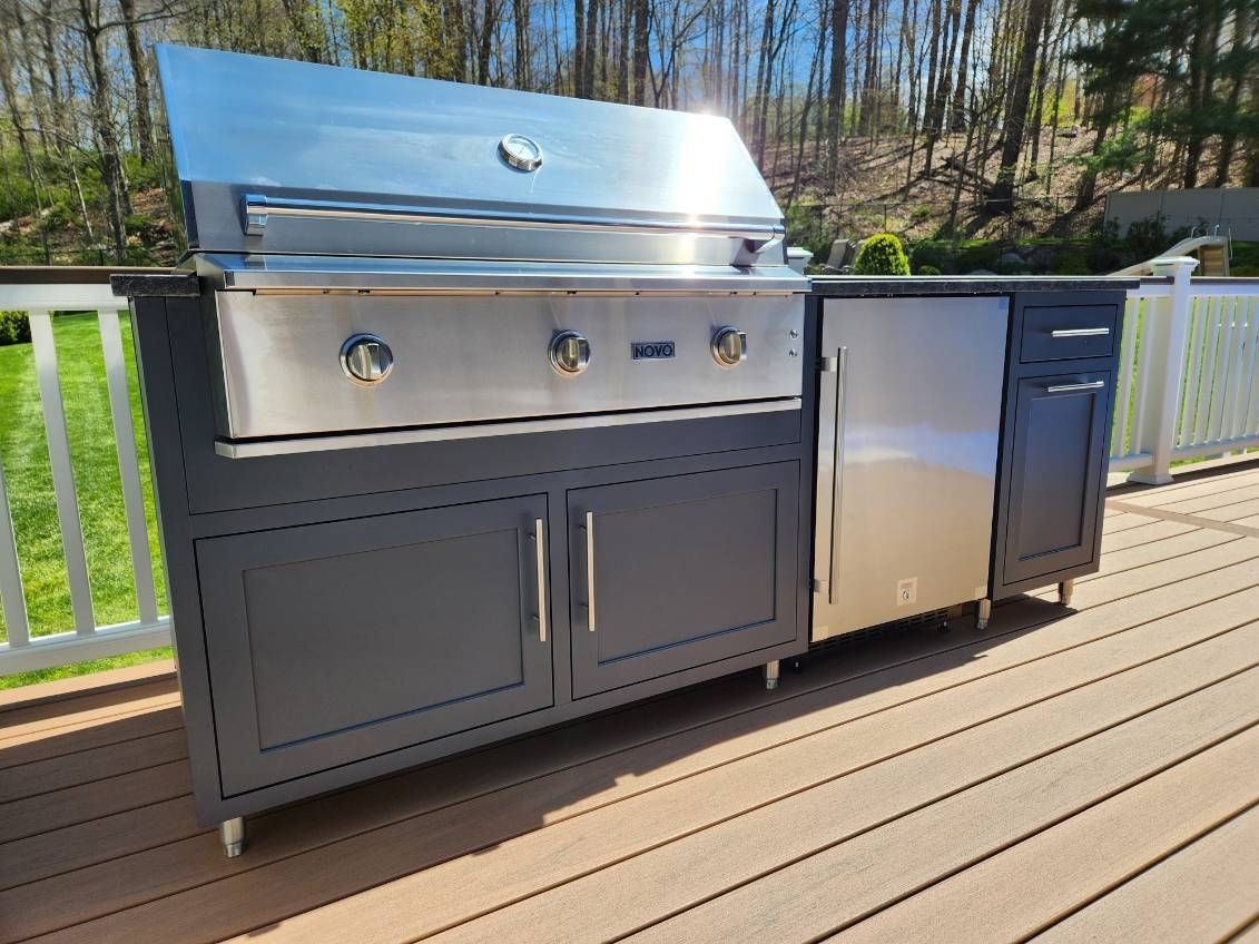 A stainless steel grill is sitting on top of a wooden deck.