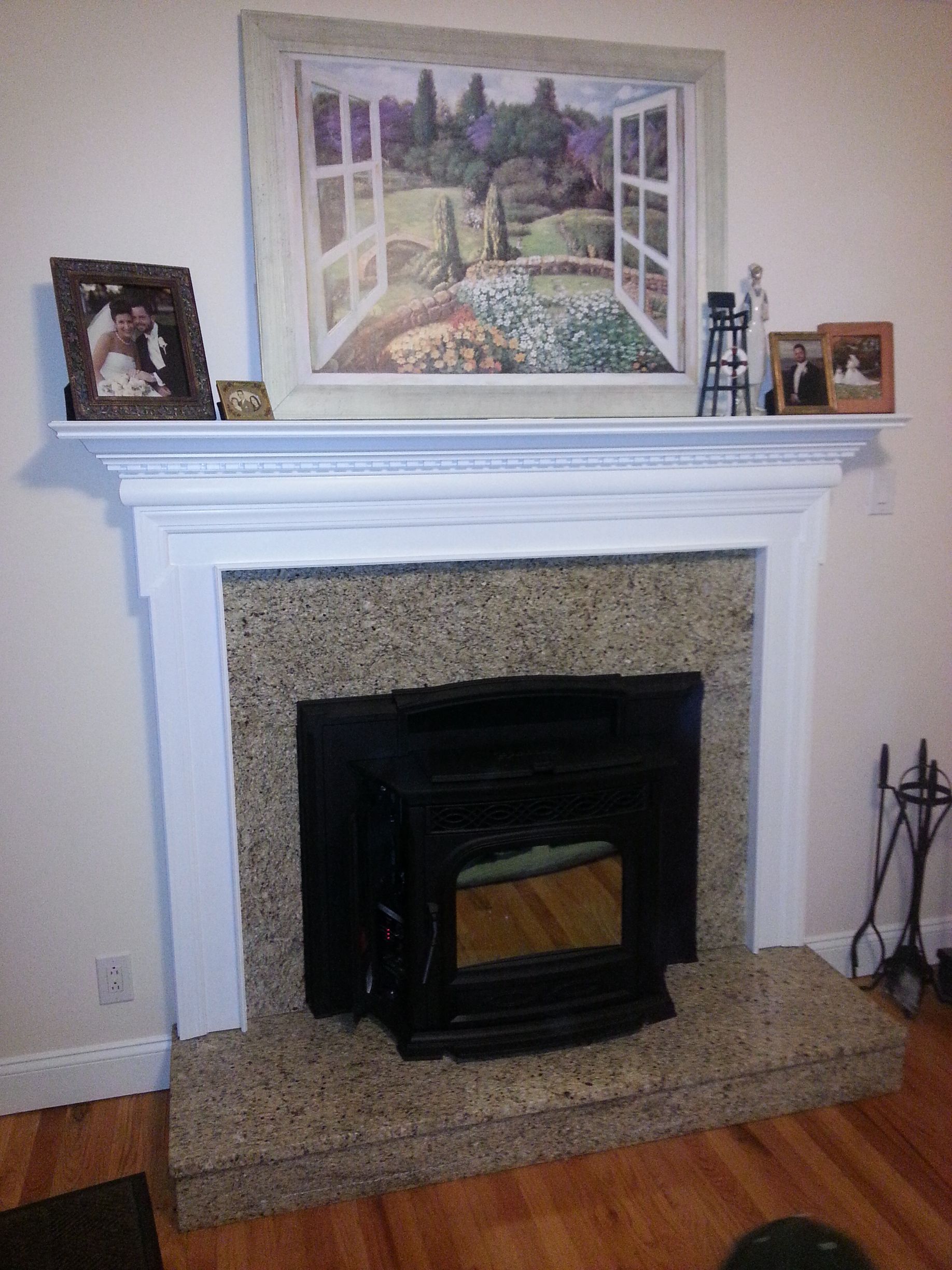A living room with a fireplace and a painting on the mantle.