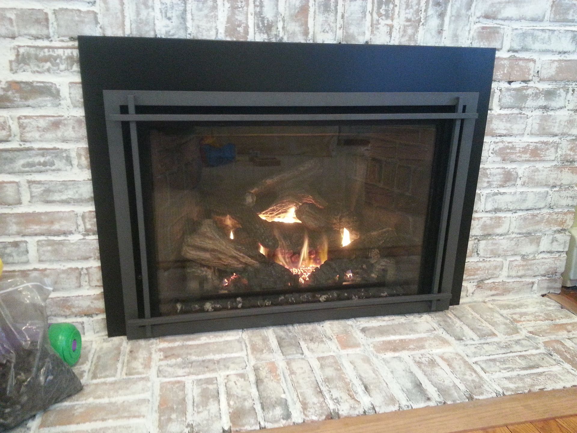 A fireplace with a black frame and a brick wall
