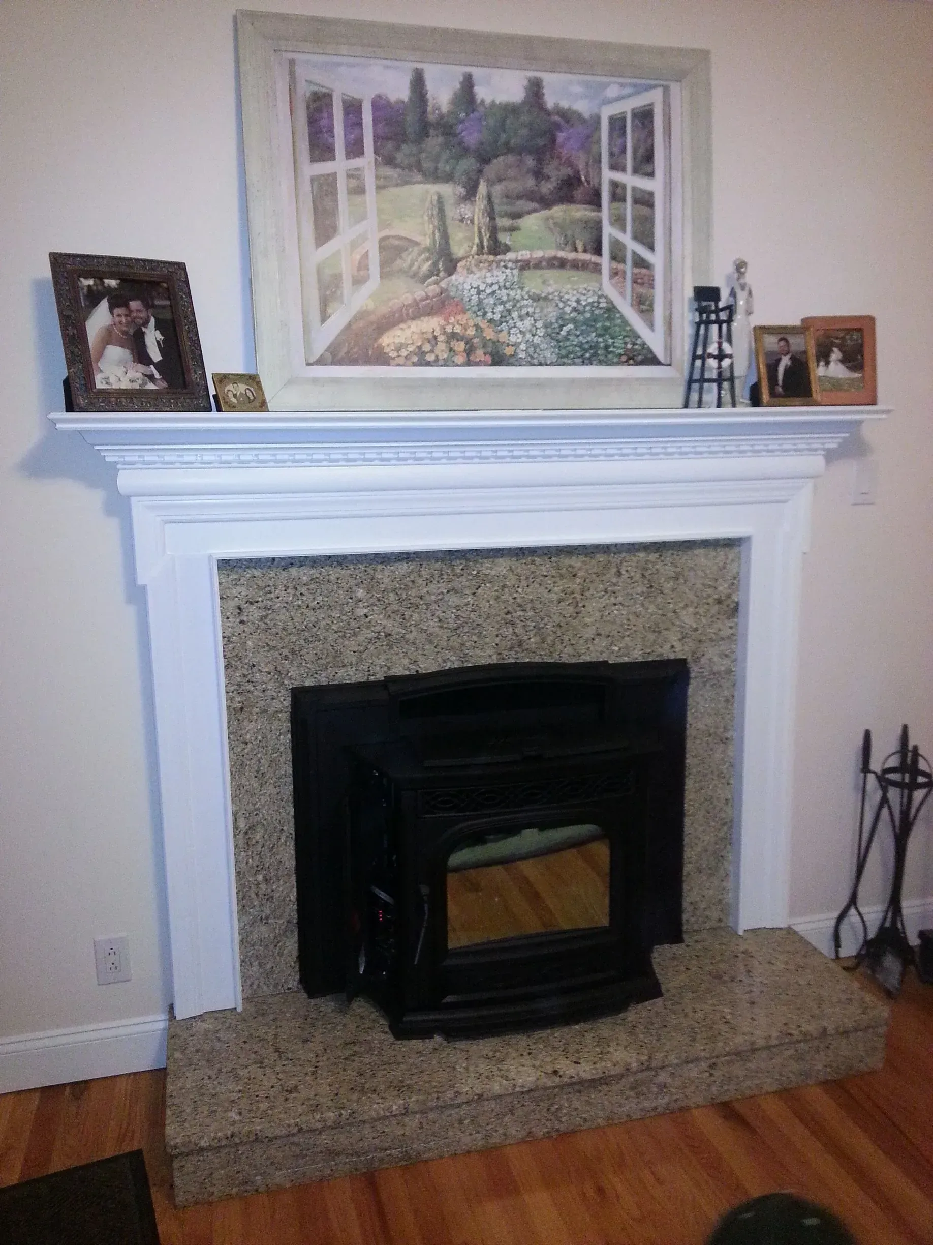 A living room with a fireplace and a painting on the mantle.