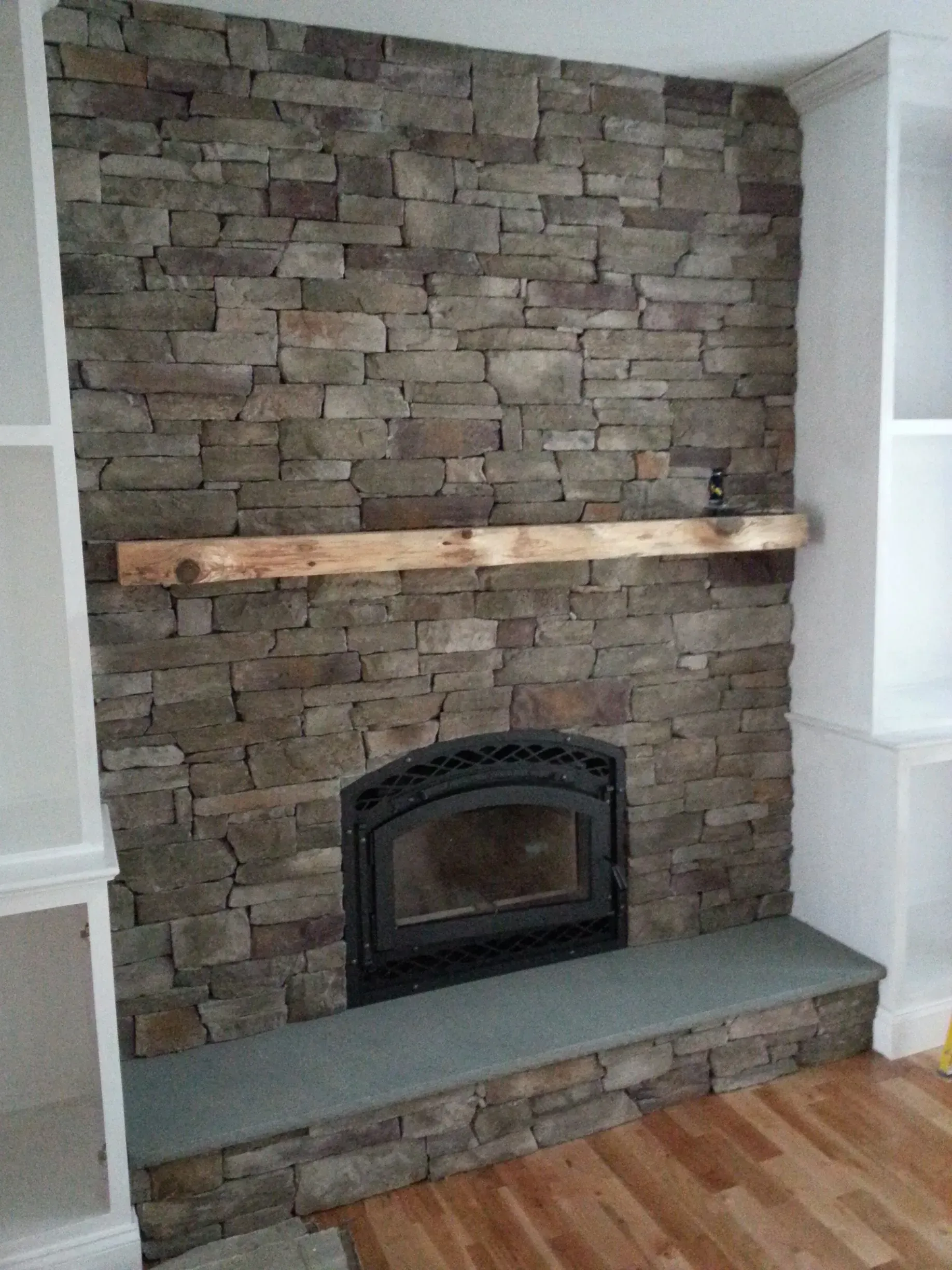 A stone fireplace with a wooden mantle in a living room.