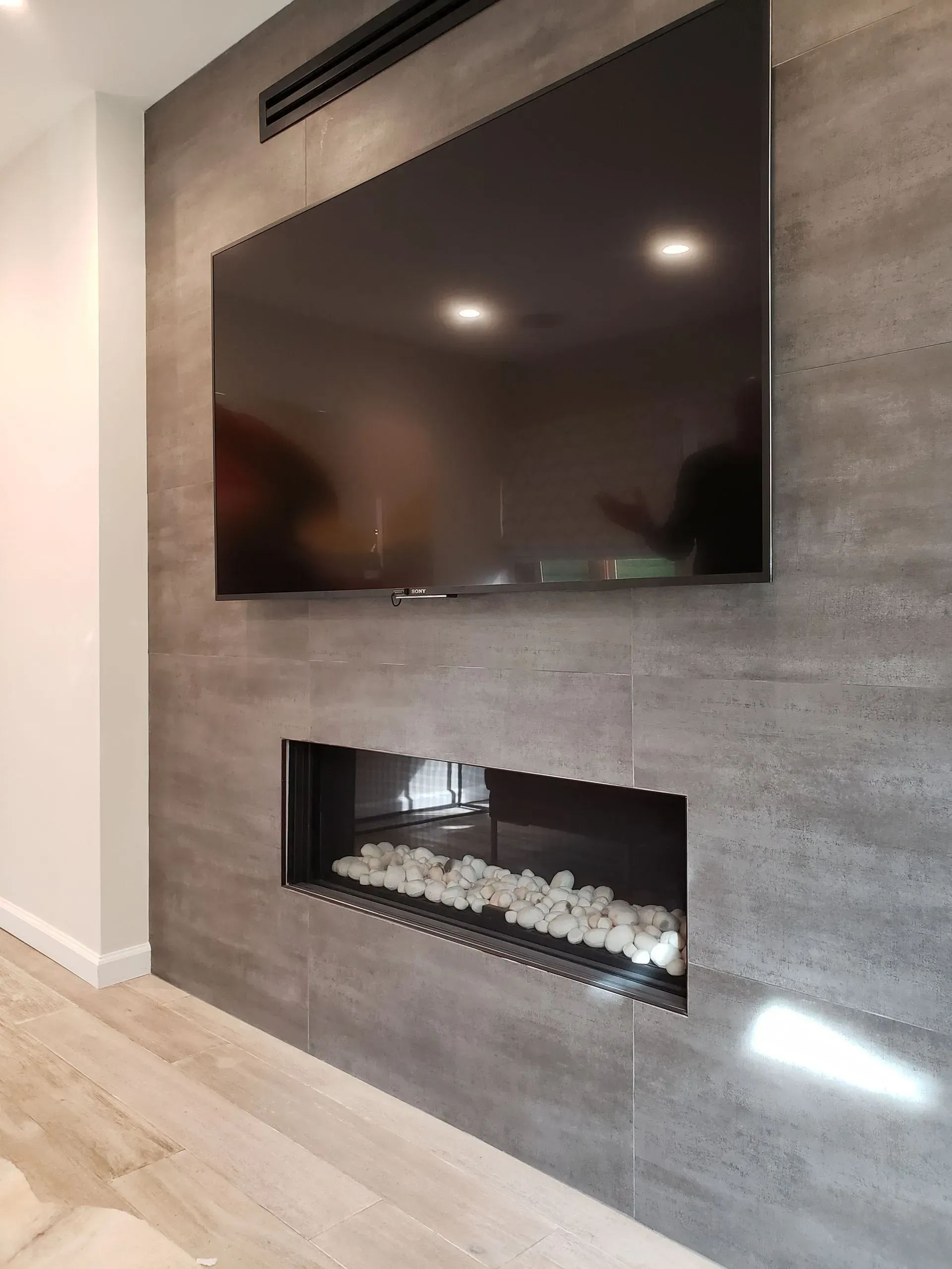 A large flat screen tv is mounted on a wall above a fireplace.