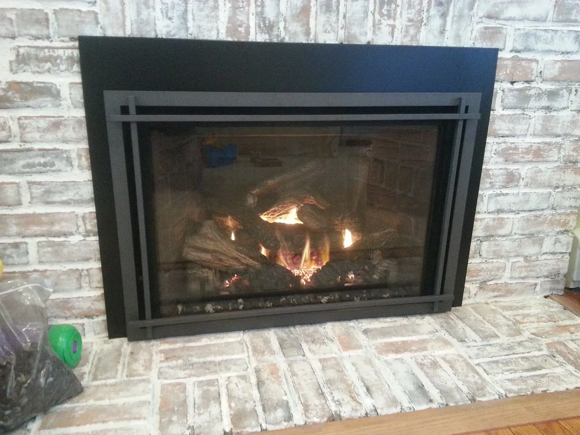 A fireplace with a black frame and a brick wall
