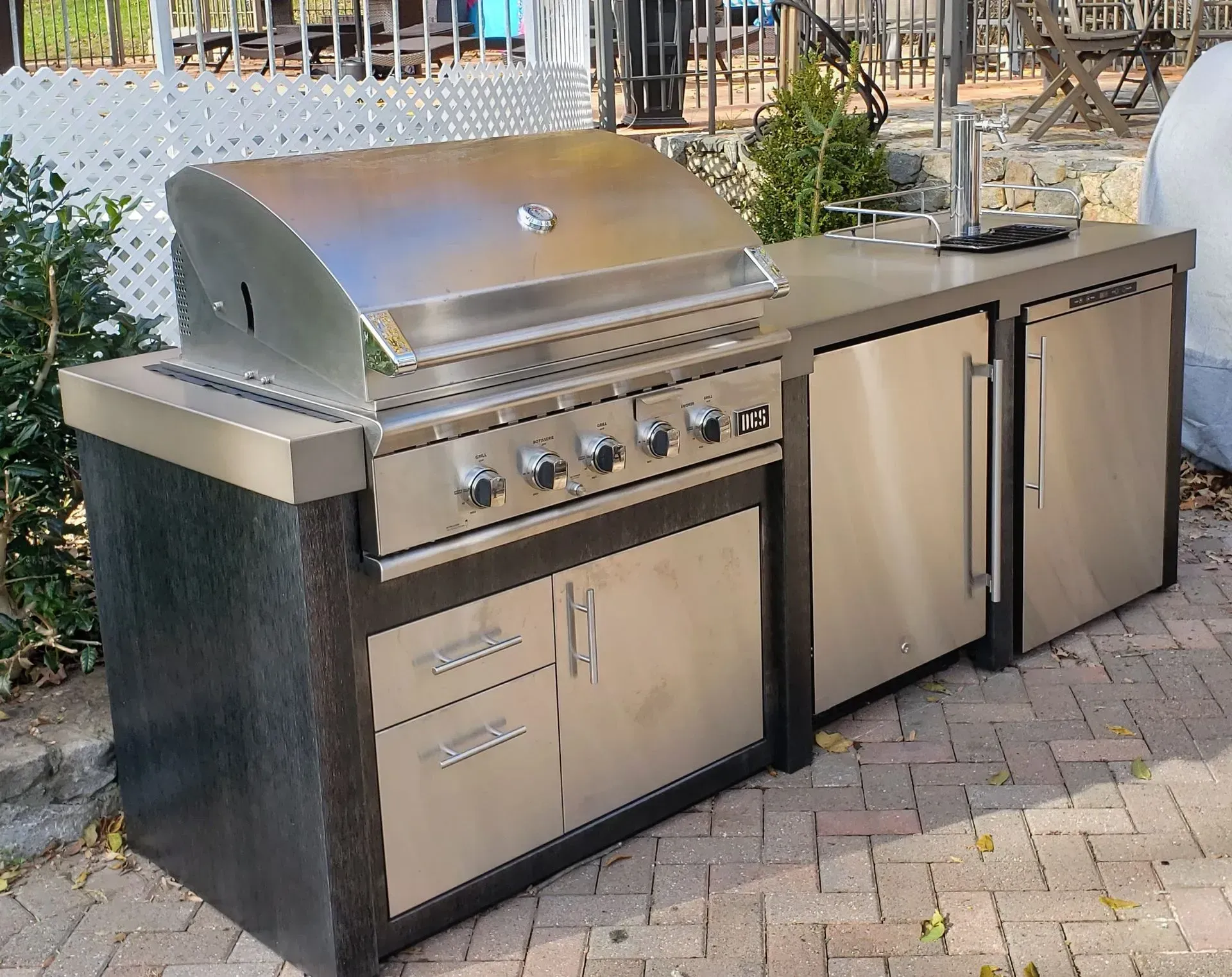 A stainless steel grill is sitting on top of a brick patio.