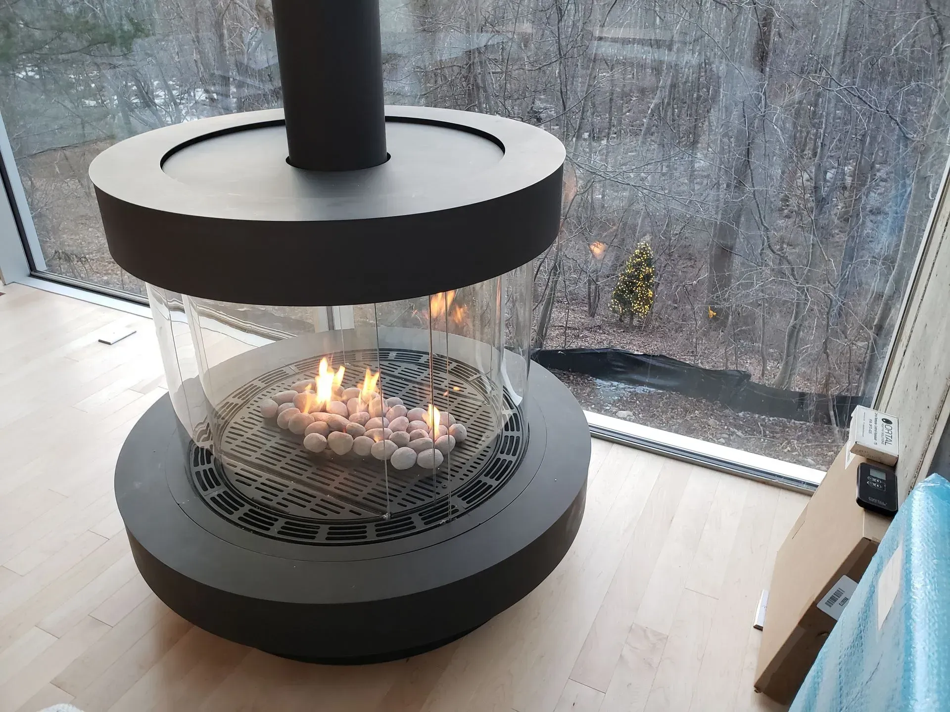 A fireplace is sitting on a wooden floor in front of a window.