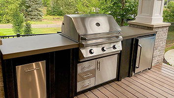 A stainless steel grill is sitting on top of a wooden deck.