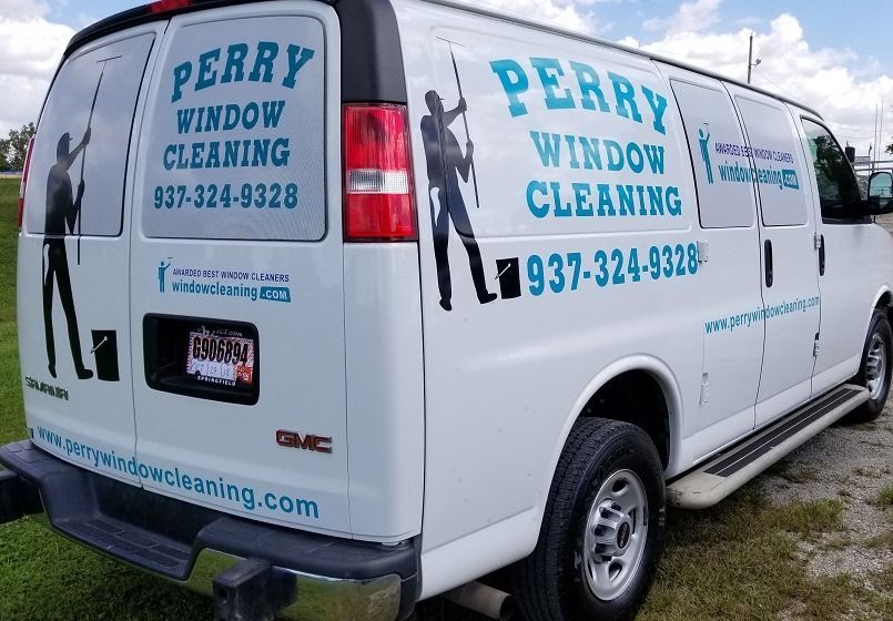 A white Perry Window Cleaning work van with branded graphics, contact information, and a website on the rear and side.
