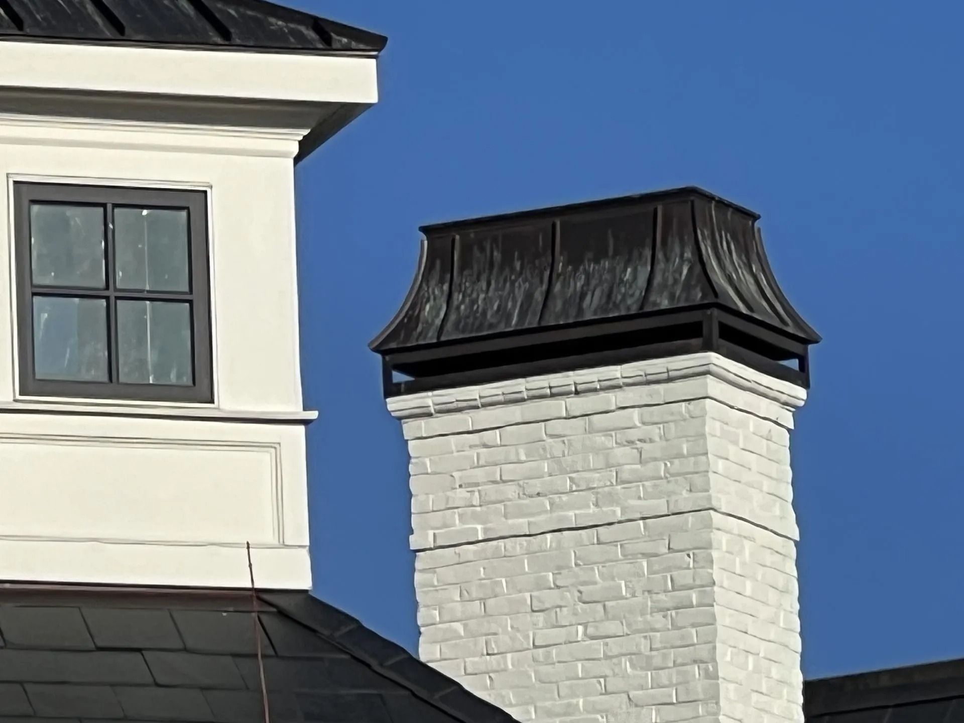 White house rooflines and a white brick chimney against a blue sky