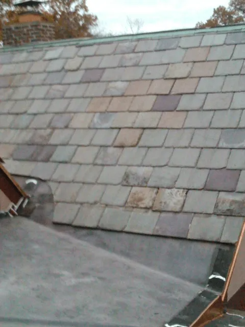 Slate roof with weathered gray shingles and a small skylight near the edge.