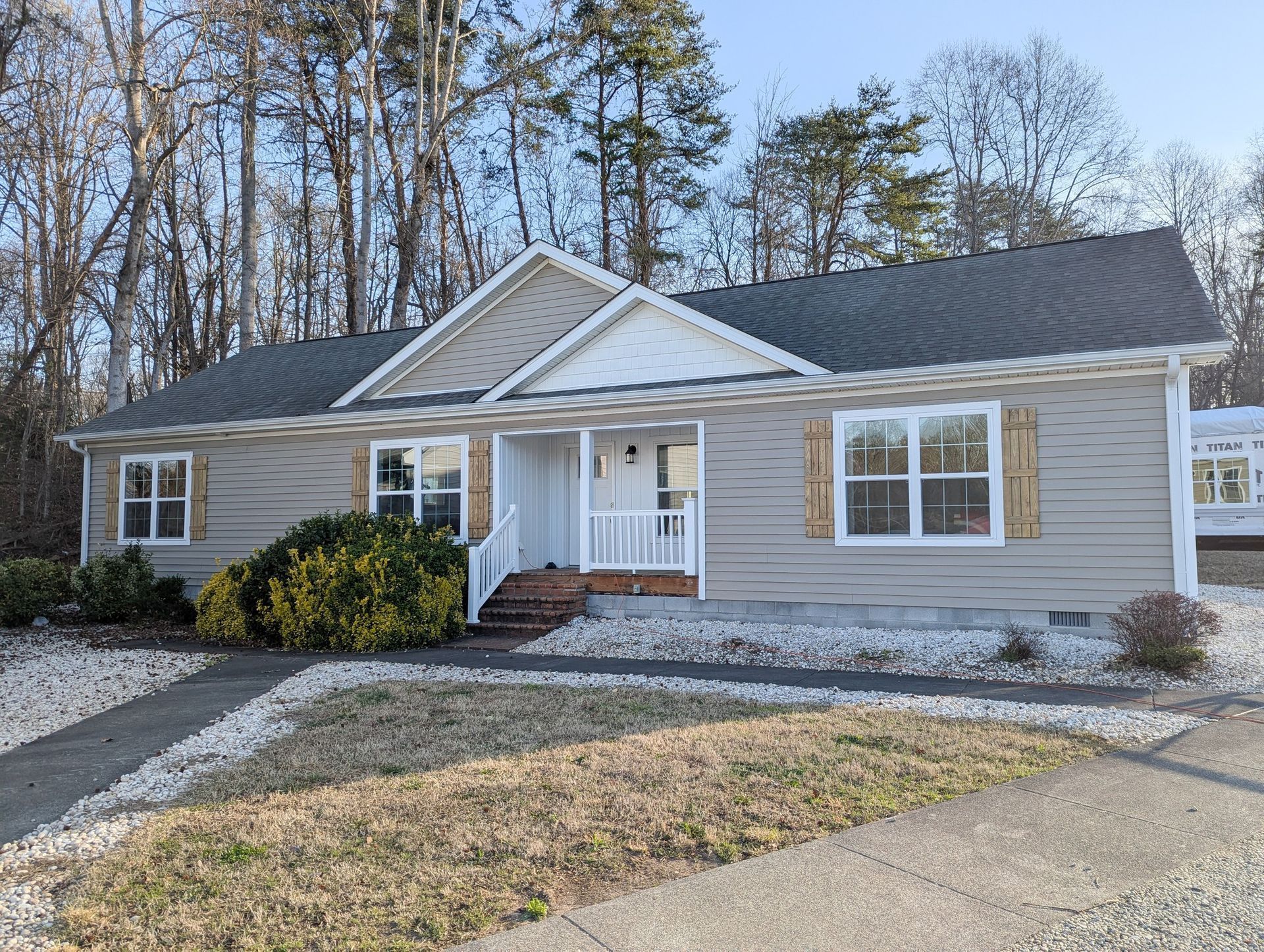 Tan house with white trim, gray roof, and gravel landscaping.