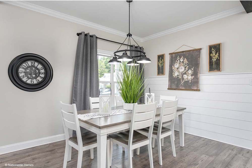 Dining room with gray walls, table, six white chairs, and a black light fixture.