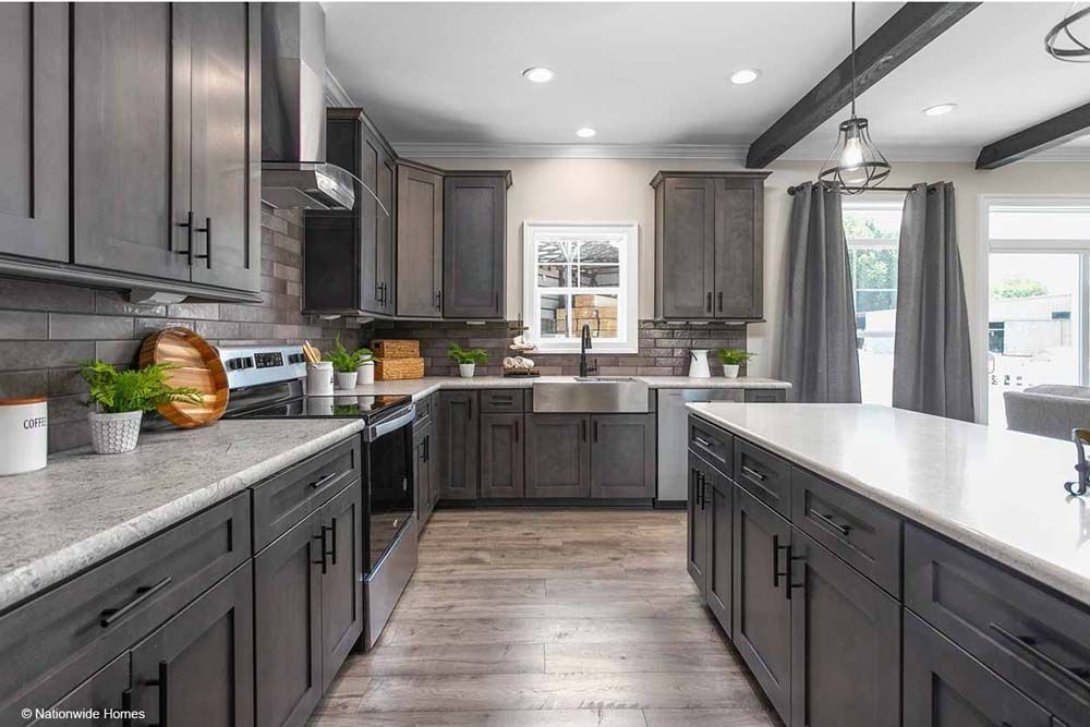 Gray kitchen with dark cabinets, white countertops, stainless steel appliances, and an island.