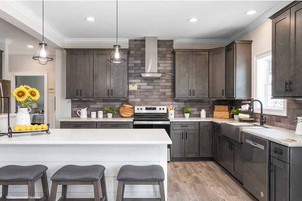 Modern kitchen with gray cabinets, white countertops, and a brick backsplash.