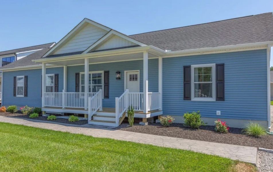 Blue house with white porch, trim, and stairs. Black shutters. Green grass and flowers in front.