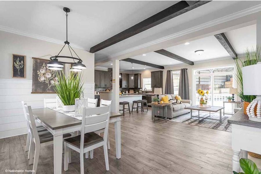 Open-concept living space with dining area, kitchen, and living room. Neutral tones, dark beams, and modern furnishings.