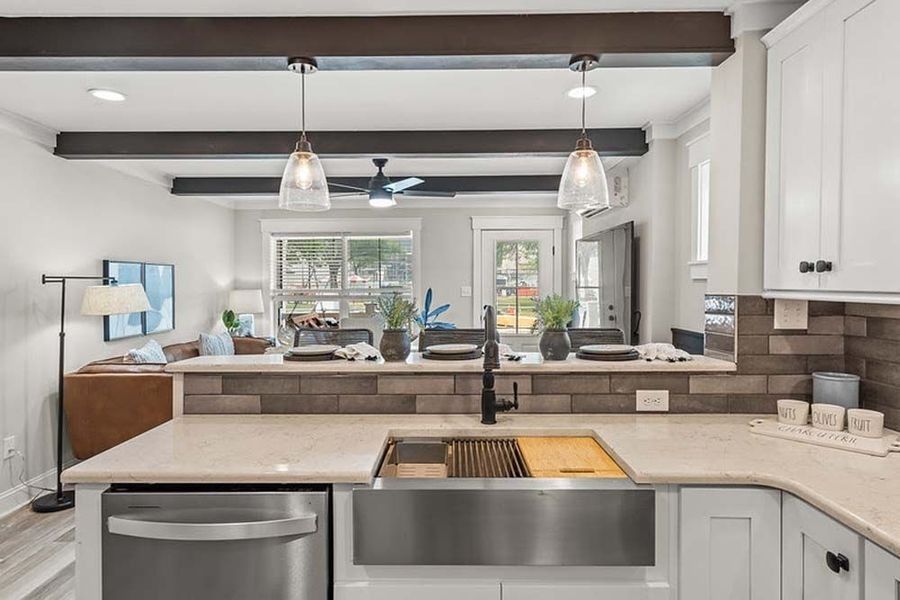 Kitchen with white cabinets, stainless steel sink, and a view of a living room with a couch.
