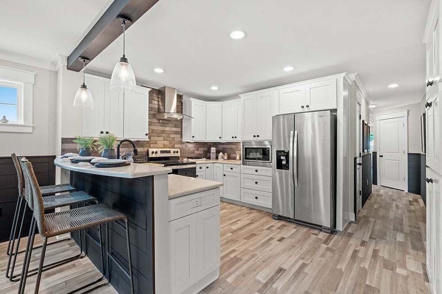 Modern kitchen with white cabinets, stainless steel appliances, island with seating.