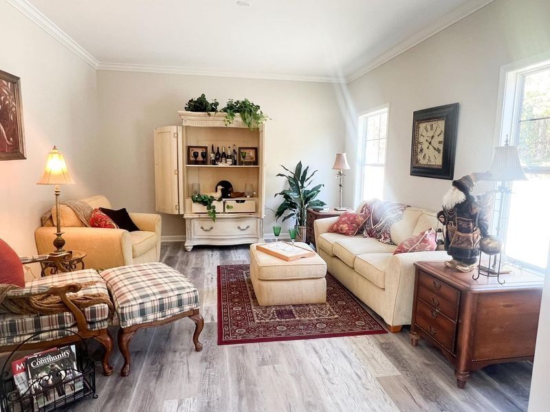 Cozy living room with cream-colored furniture, a red rug, and wooden accents.