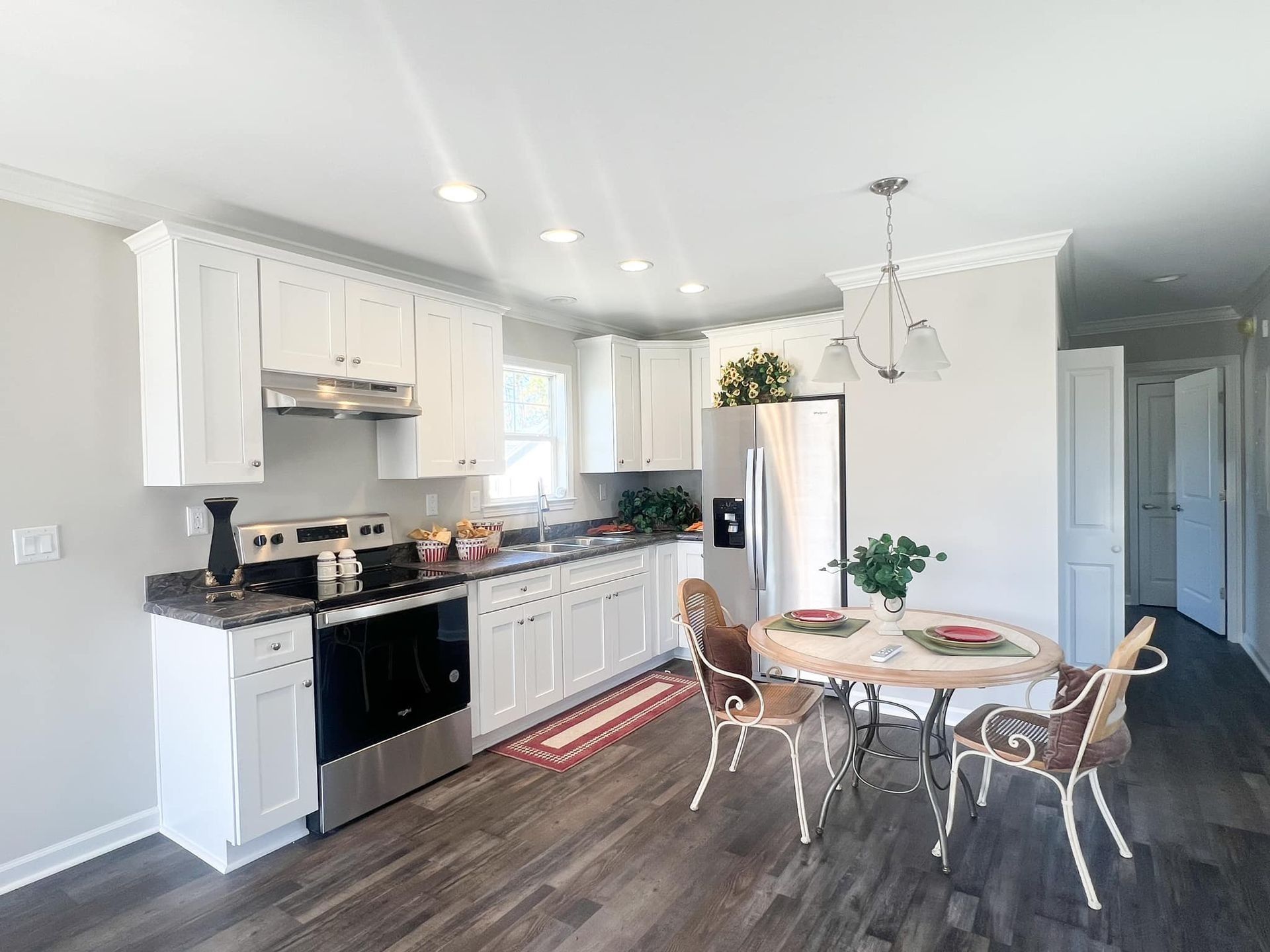 White kitchen with dark counters, stainless steel appliances, and a round dining table.