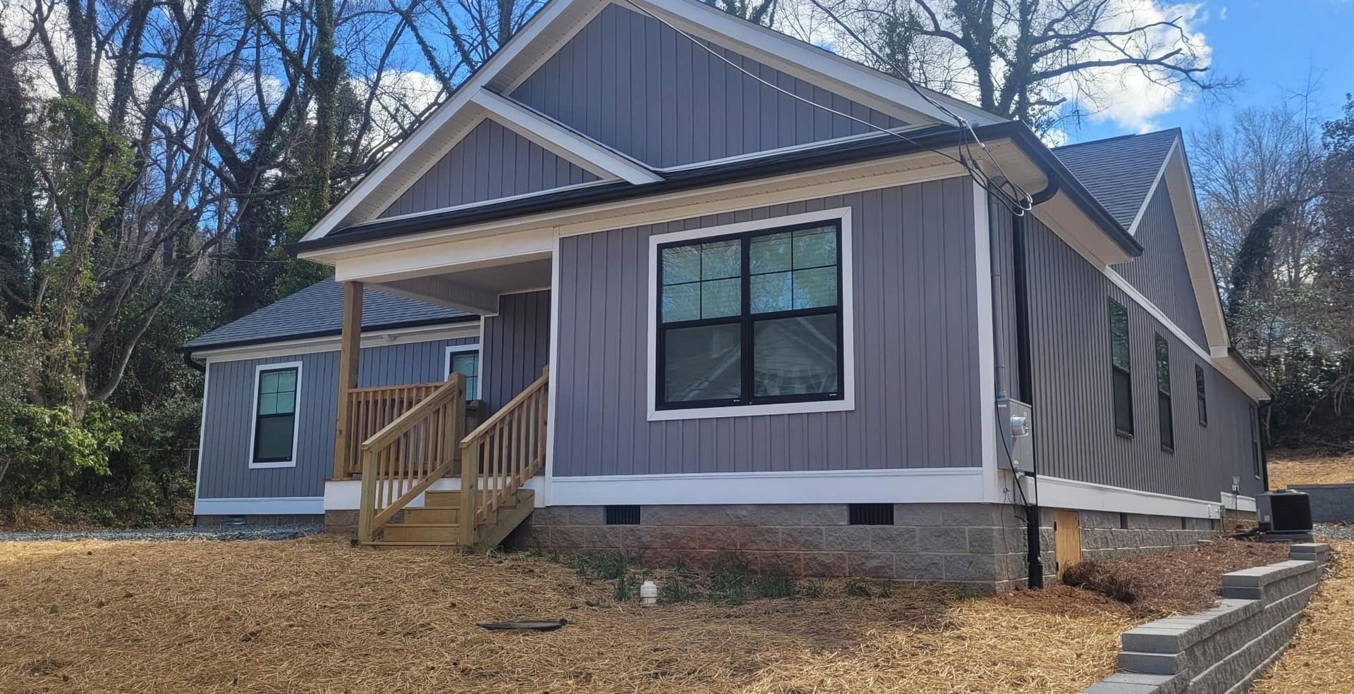 Gray siding on a new house with a small porch and black framed windows.