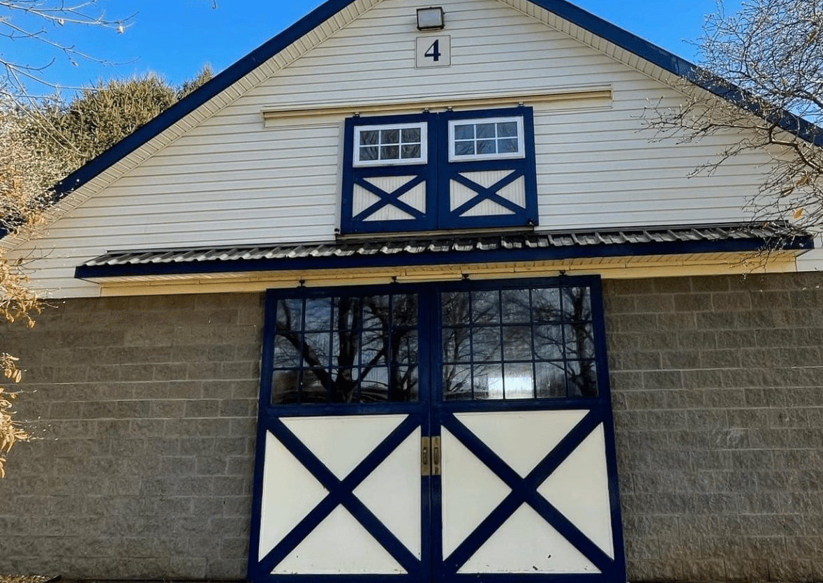 White building with blue trim, large doors, and small upper window, 