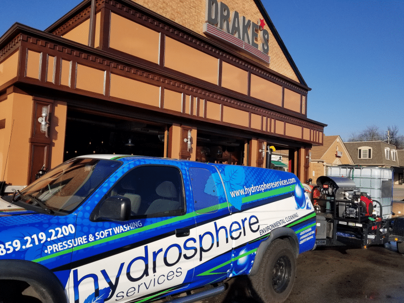 HydroSphere Services truck parked in front of Drake's building, indicating pressure washing services.