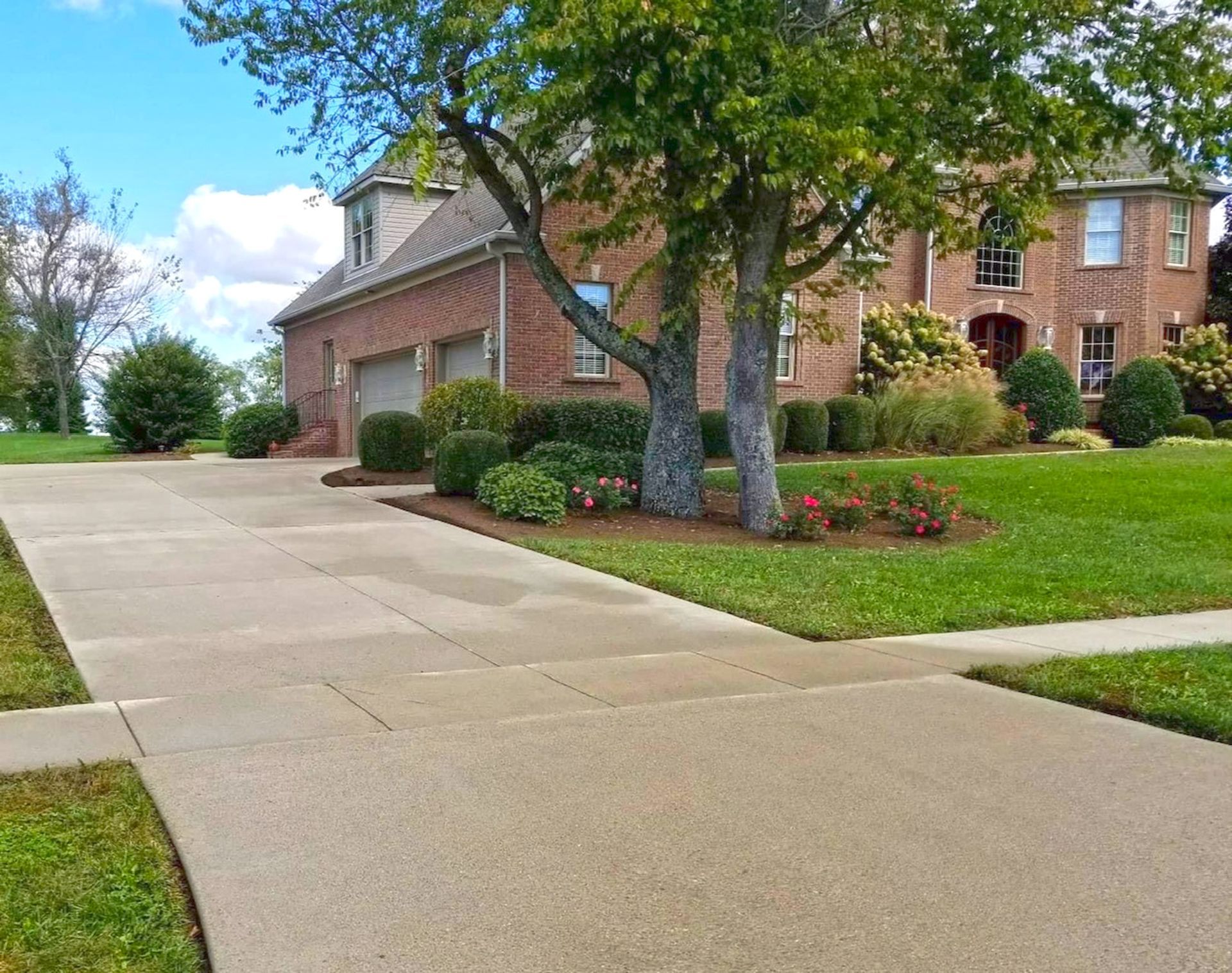 Person using a surface cleaner on a concrete sidewalk, creating a wet, clean path.