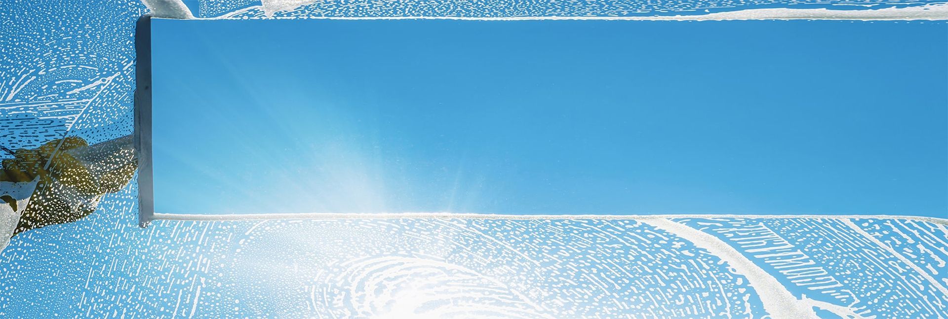 A mirror reflects a bright blue sky, surrounded by white abstract patterns, perhaps snow or water.