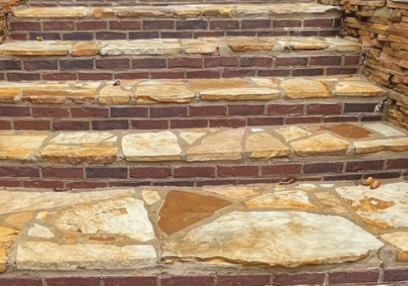 Brick and stone outdoor staircase. Brown bricks alternate with tan, irregularly shaped stones.