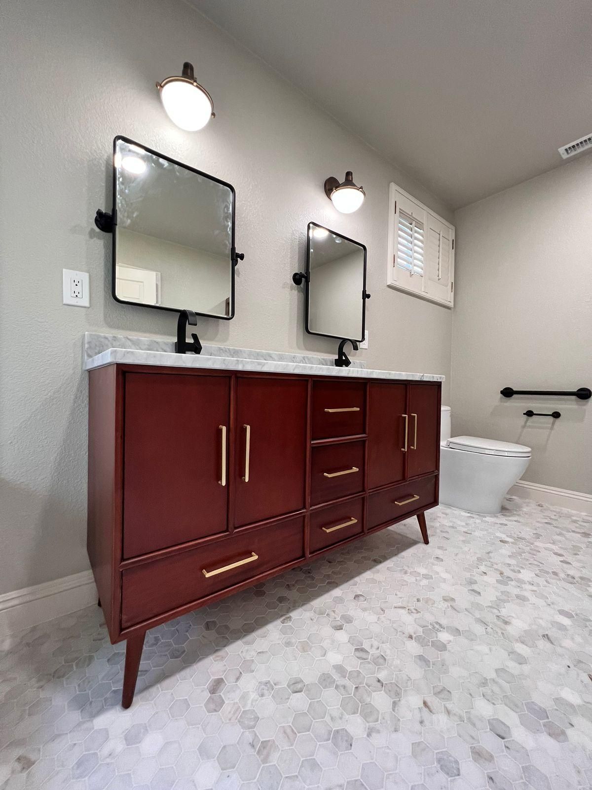 Bathroom with a red vanity, mirrors, and a toilet. White marble floor.