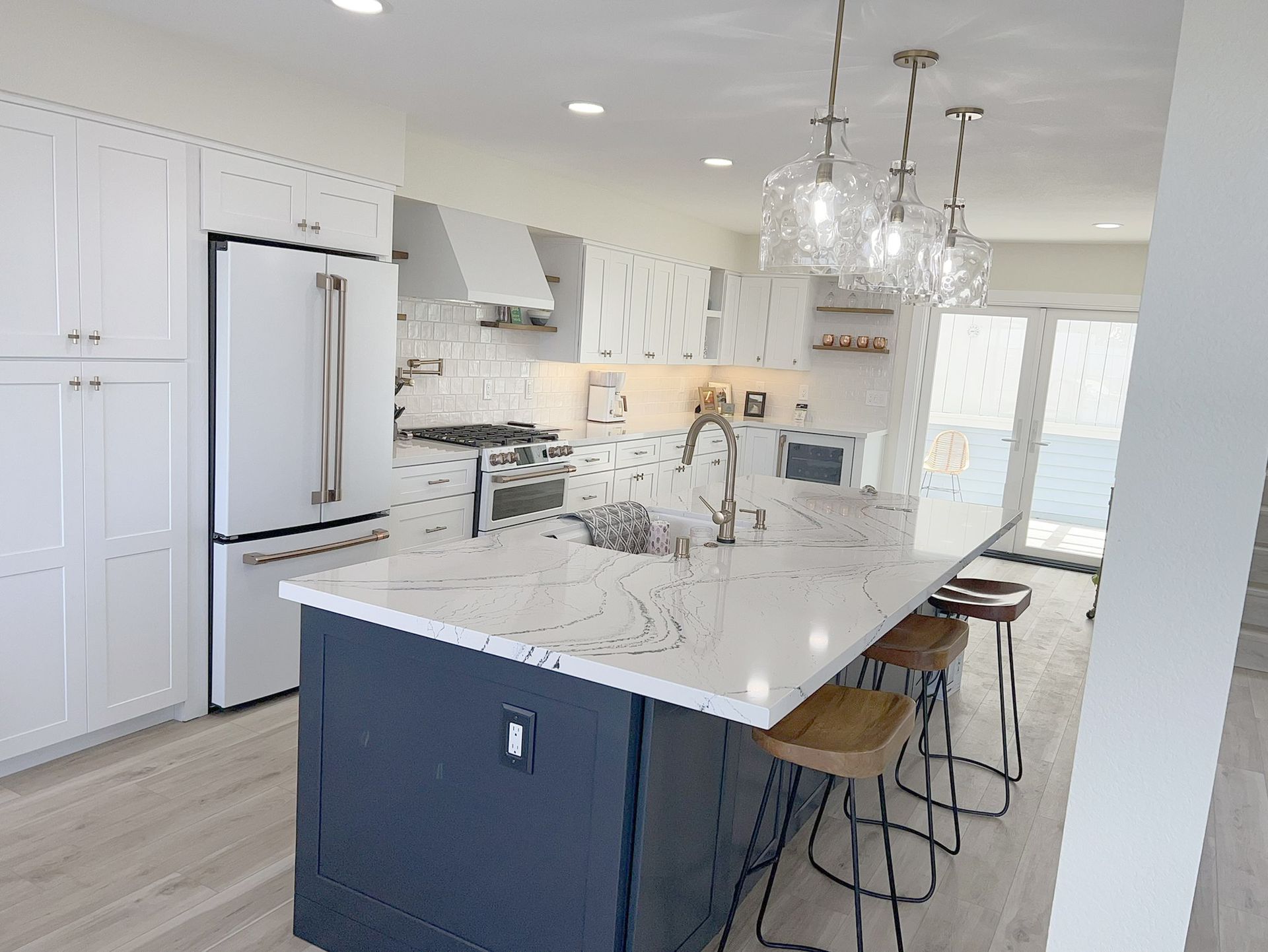 Modern kitchen with white cabinets, dark blue island, and a long countertop.